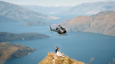 Queenstown New Zealand Elopement Wedding Photographer - A bride and groom standing on top of Coromandel Peak with a helicopter in the background.