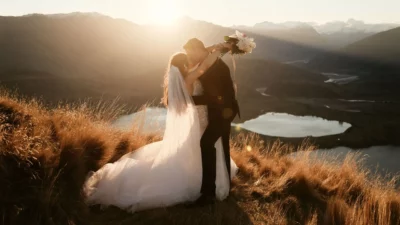Queenstown New Zealand Elopement Wedding Photographer - A bride and groom kiss on top of Coromandel Peak, overlooking a lake.