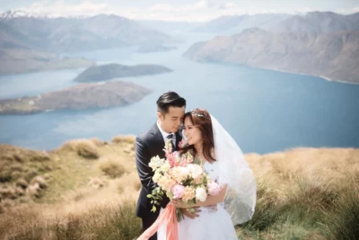 Queenstown New Zealand Elopement Wedding Photographer - A bride and groom standing on top of a peak overlooking lake wanaka.
