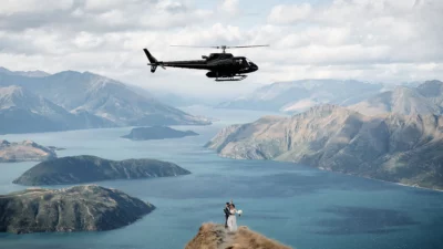 Queenstown New Zealand Elopement Wedding Photographer - A bride and groom standing on top of Coromandel Peak with a helicopter flying over them.