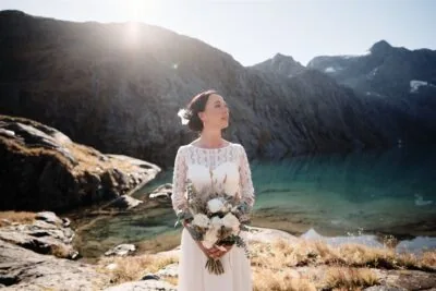 Queenstown New Zealand Elopement Wedding Photographer - A bride standing in front of Lake Erskine with her bouquet.