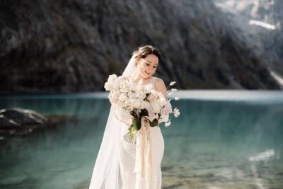 Queenstown New Zealand Elopement Wedding Photographer - A bride holding a bouquet in front of Lake Erskine.