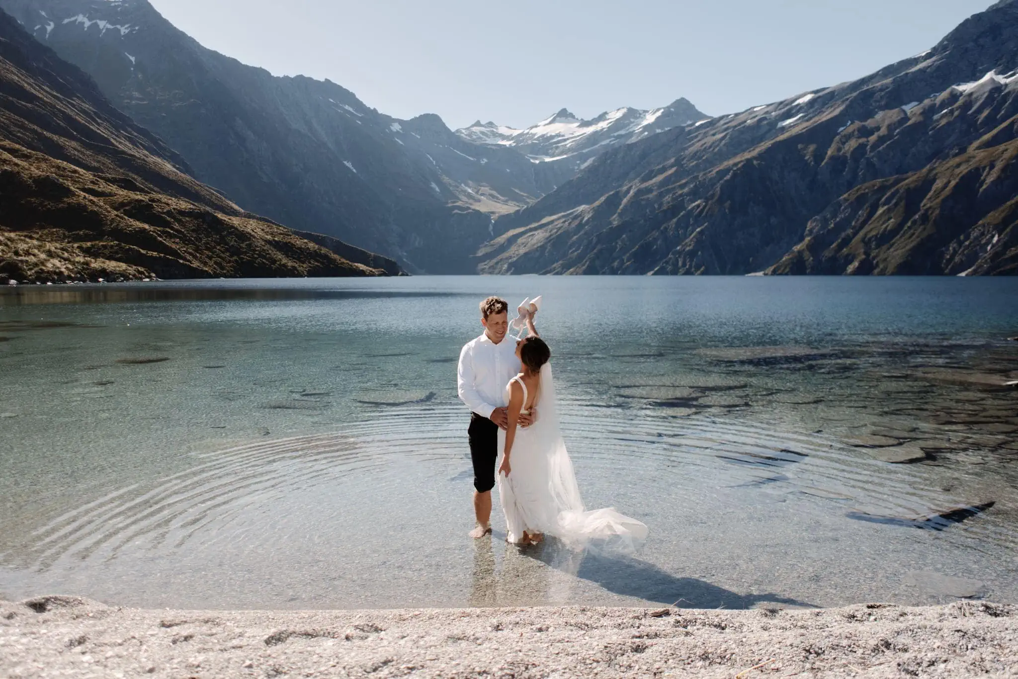 Queenstown New Zealand Elopement Wedding Photographer - A bride and groom standing in the shallow water of Lake Lochnagar in New Zealand.