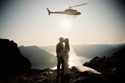 Queenstown New Zealand Elopement Wedding Photographer - A bride and groom share a romantic kiss in front of a helicopter at the Remarkables.