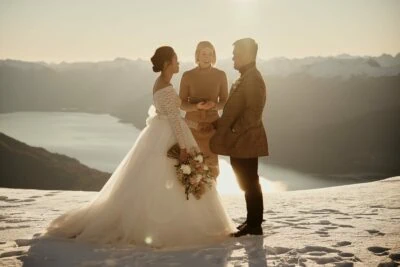 Queenstown New Zealand Elopement Wedding Photographer - A bride and groom standing on top of the Remarkables, a snowy mountain, with a lake in the background.
