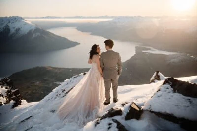 Queenstown New Zealand Elopement Wedding Photographer - SEO-optimized description of a remarkable scene featuring the bride and groom standing on top of a mountain overlooking Lake Wanaka.