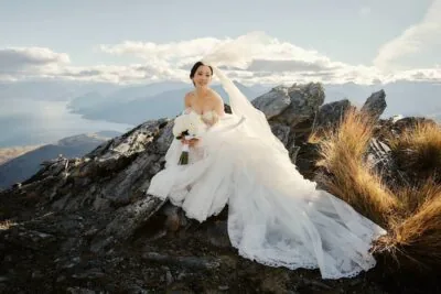 Queenstown New Zealand Elopement Wedding Photographer - A bride sitting on top of the Remarkables, with mountains in the background.