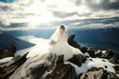 Queenstown New Zealand Elopement Wedding Photographer - A bride sits on top of the Remarkables overlooking Lake Wanaka.
