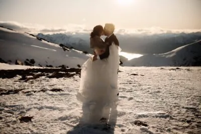 Queenstown New Zealand Elopement Wedding Photographer - A bride and groom sharing a romantic kiss on top of the Remarkables, a snow covered mountain.