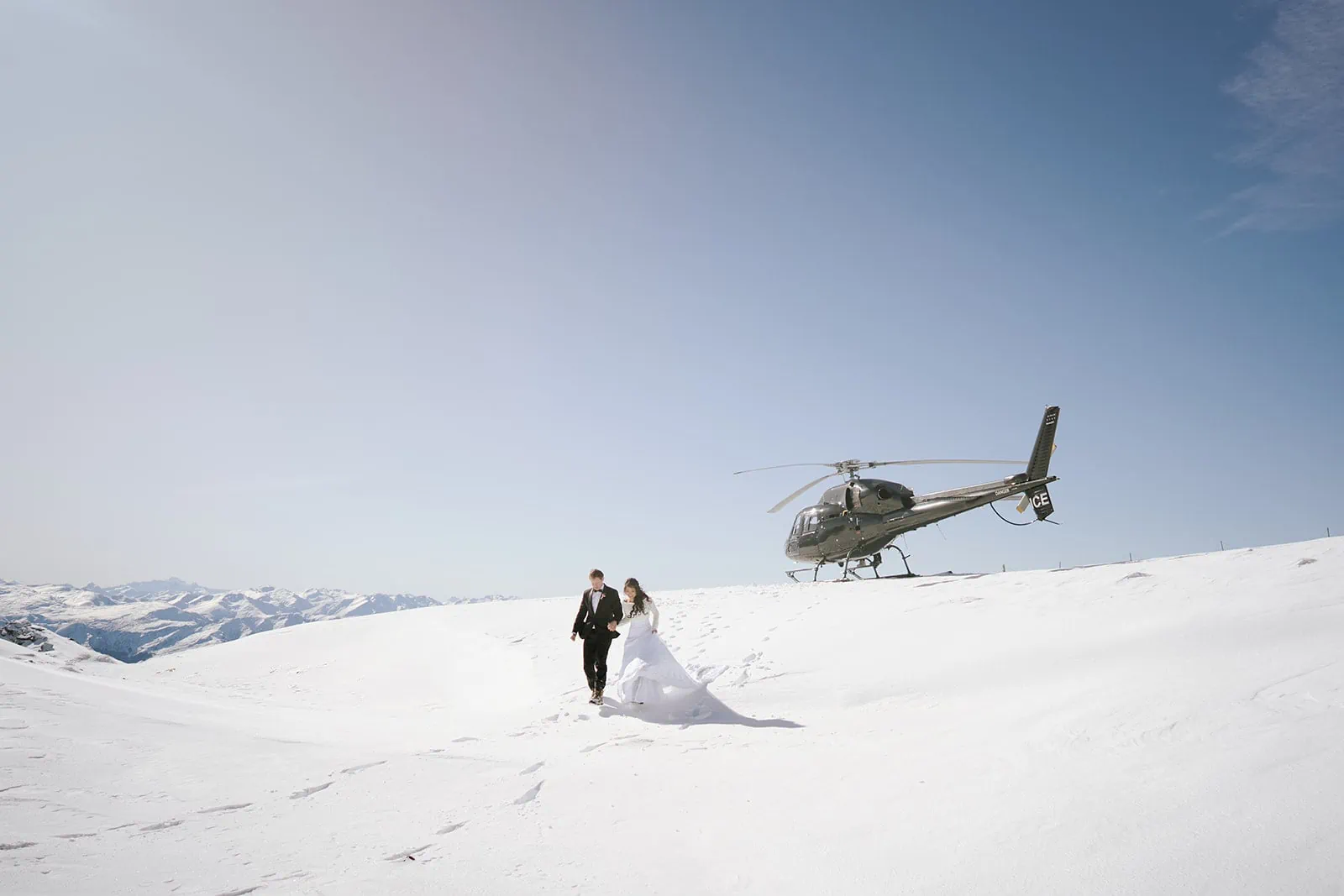Queenstown New Zealand Elopement Wedding Photographer - A bride and groom standing next to a helicopter in snowy Queenstown, New Zealand.