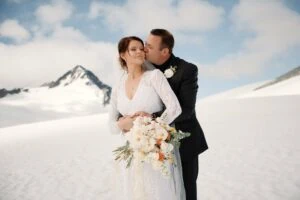 Queenstown New Zealand Elopement Wedding Photographer - A bride and groom embracing near Tyndall Glacier in the snow.