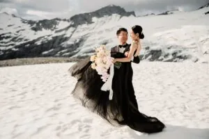 Queenstown New Zealand Elopement Wedding Photographer - A bride and groom standing in the snow with Tyndall Glacier in the background.