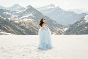 Queenstown New Zealand Elopement Wedding Photographer - A woman in a blue dress standing on top of Tyndall Glacier, a snowy mountain.