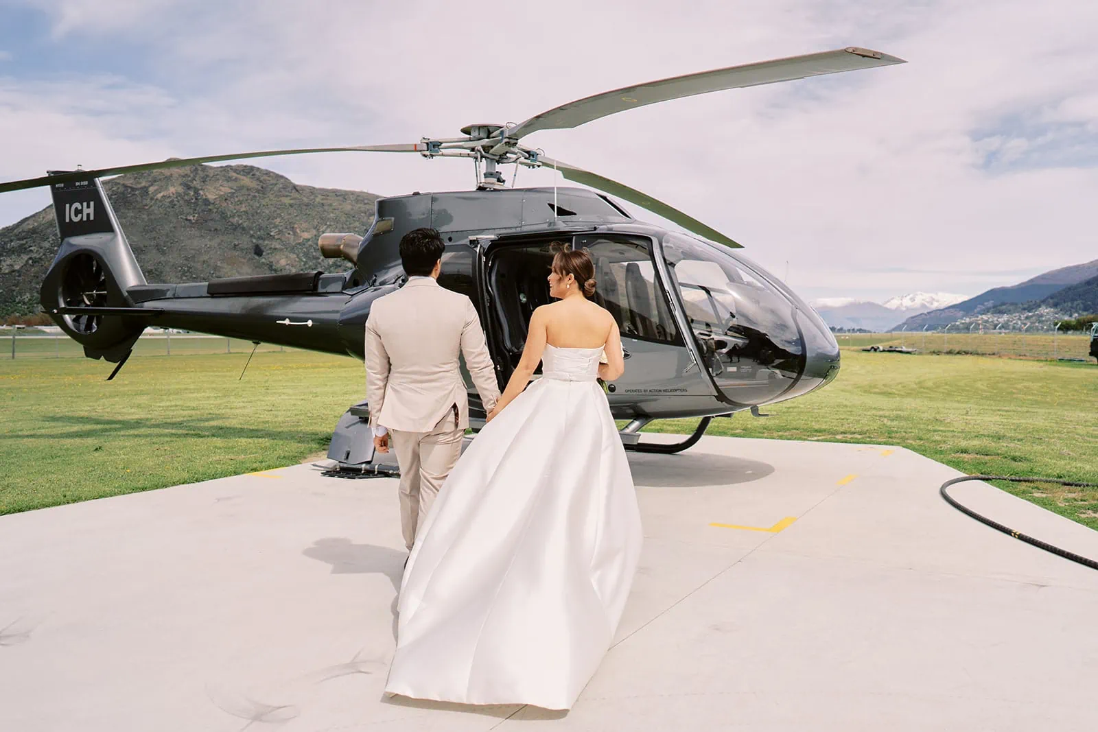 Queenstown Elopement Heli Wedding Photographer クイーンズタウン結婚式 | Ceidi and Tobi, a bride and groom, elegantly walk towards a helicopter for their Queenstown wedding.
