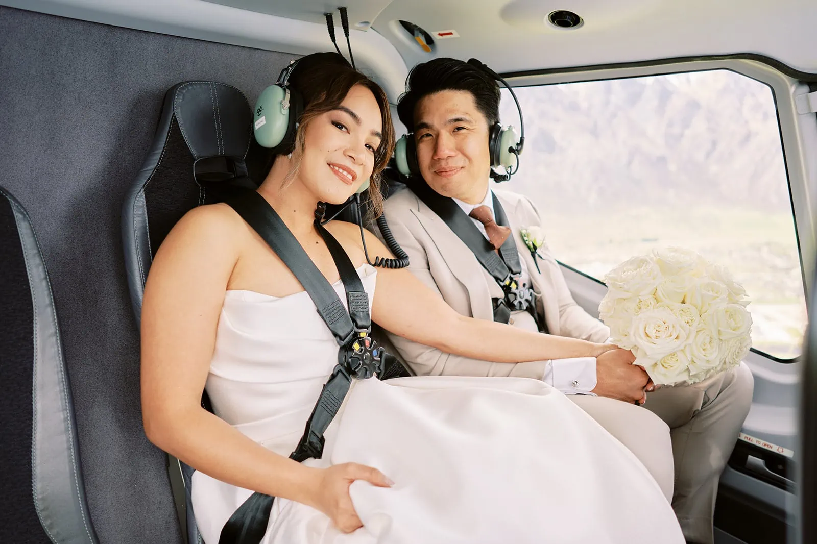 Queenstown Elopement Heli Wedding Photographer クイーンズタウン結婚式 | A bride and groom sitting in the back of a helicopter overlooking Queenstown.