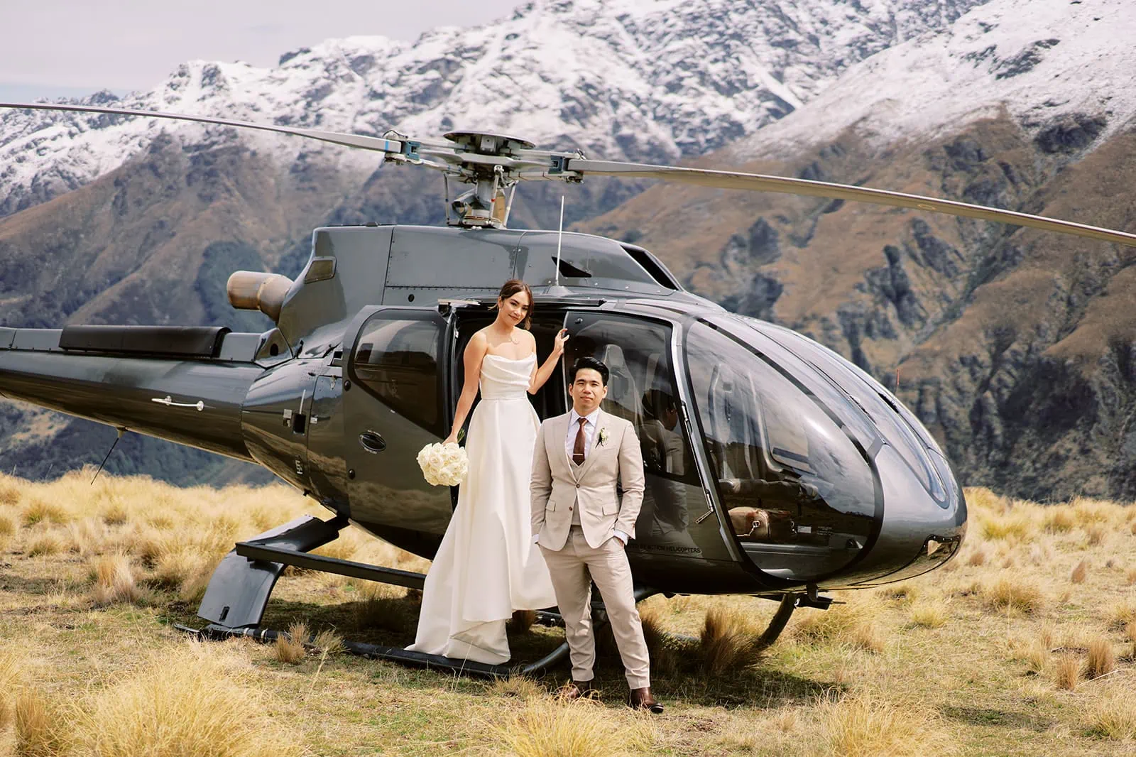 Queenstown Elopement Heli Wedding Photographer クイーンズタウン結婚式 | Ceidi & Tobi, a bride and groom, posing next to a helicopter during their Queenstown wedding at StoneRidge.