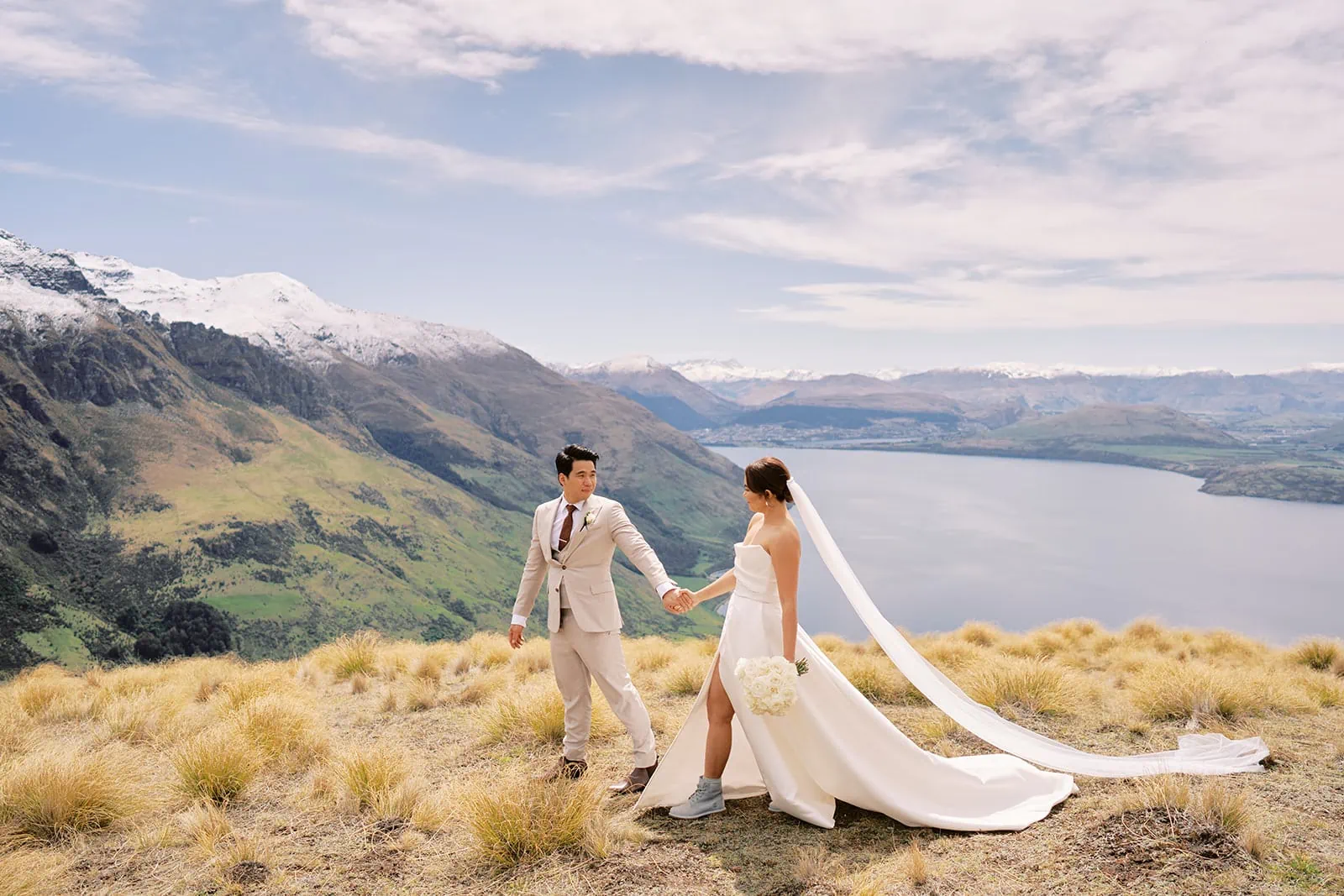 Queenstown Elopement Heli Wedding Photographer クイーンズタウン結婚式 | A bride and groom standing on top of a hill overlooking Lake Wanaka in Queenstown.