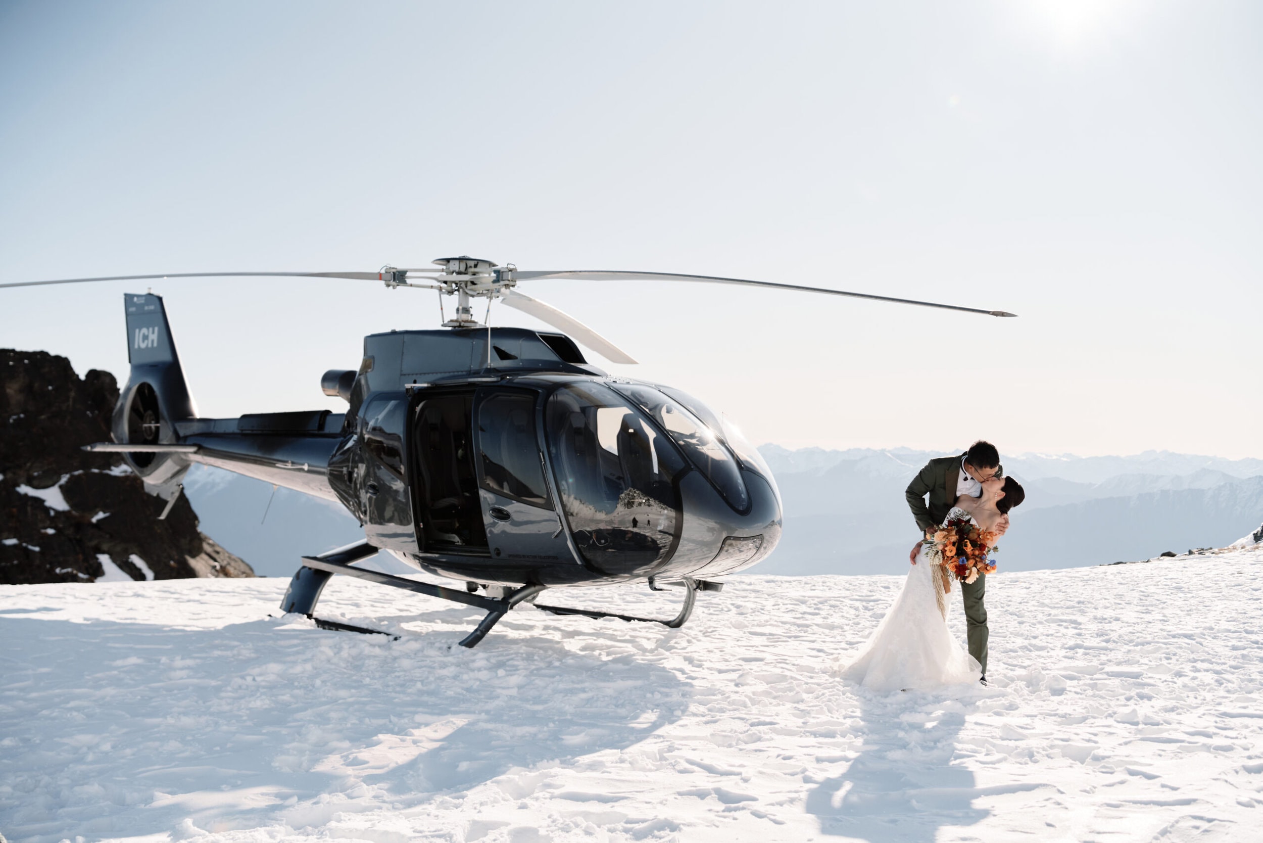 Queenstown Wedding Photographer A bride and groom kiss in front of a heli in Queenstown during their pre wedding shoot.