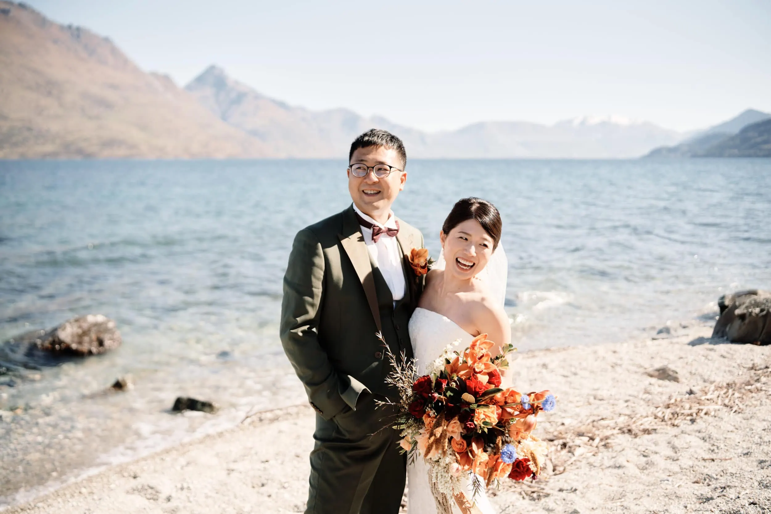 Queenstown Wedding Photographer A bride and groom standing on the shore of Lake Wanaka in Queenstown.