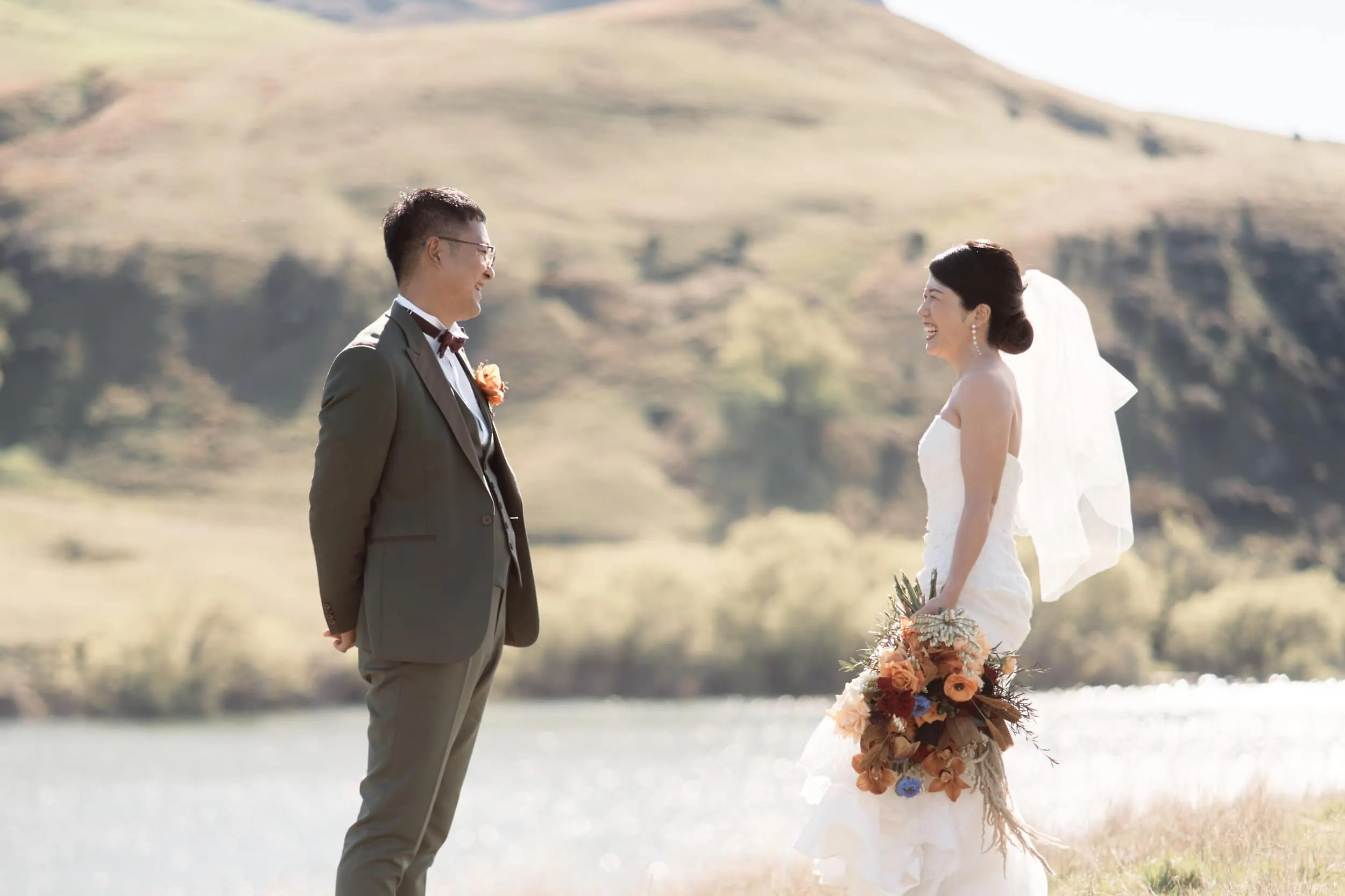 Queenstown Wedding Photographer A bride and groom standing in front of a lake.