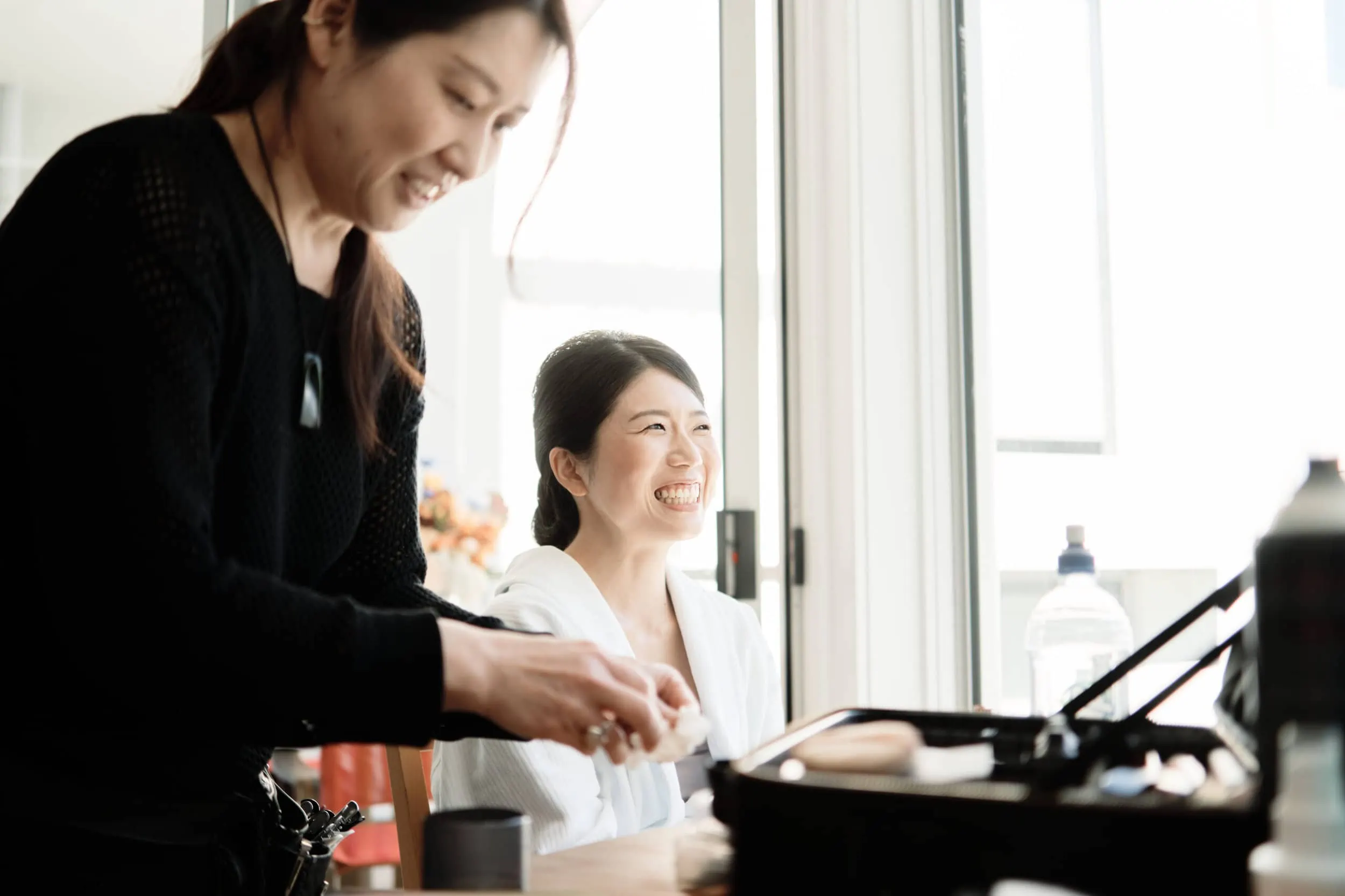 Queenstown Wedding Photographer Two Asian women, Asumi and Atsushi, working on makeup in a kitchen in Queenstown.