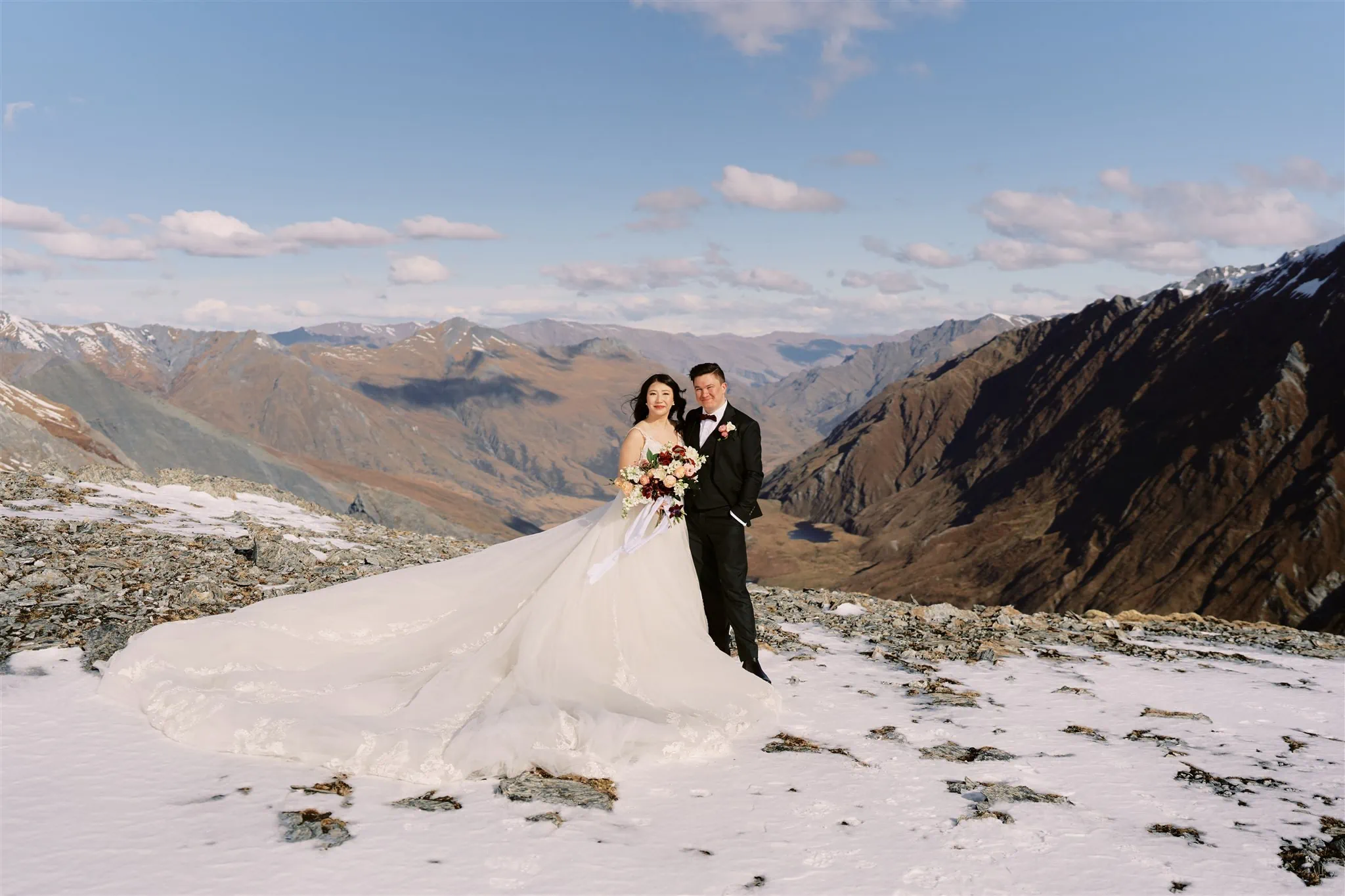 Queenstown Elopement Heli Wedding Photographer クイーンズタウン結婚式 | An elopement wedding of a bride and groom standing on top of a snowy mountain.