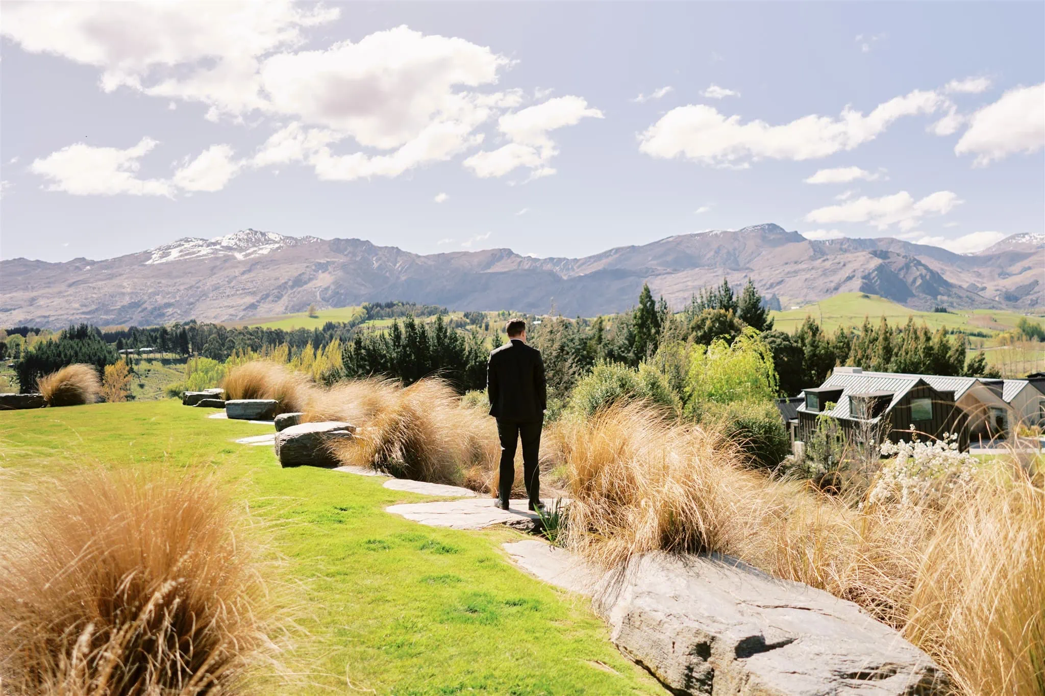 Queenstown Elopement Heli Wedding Photographer クイーンズタウン結婚式 | Alex & Michael's elopement wedding at Roy's Peak, with mountains in the background as the man stands in a grassy area.