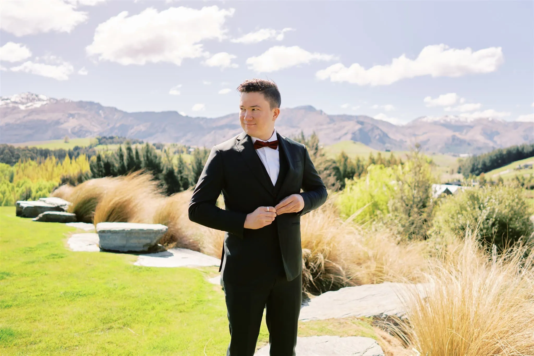 Queenstown Elopement Heli Wedding Photographer クイーンズタウン結婚式 | A man in a tuxedo posing in front of Roy's Peak mountains.