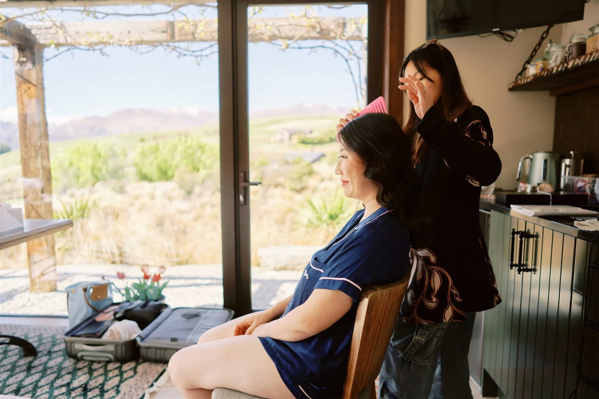 Queenstown Elopement Heli Wedding Photographer クイーンズタウン結婚式 | A woman getting her hair done in front of a window while planning an elopement with Alex & Michael at Roy's Peak.