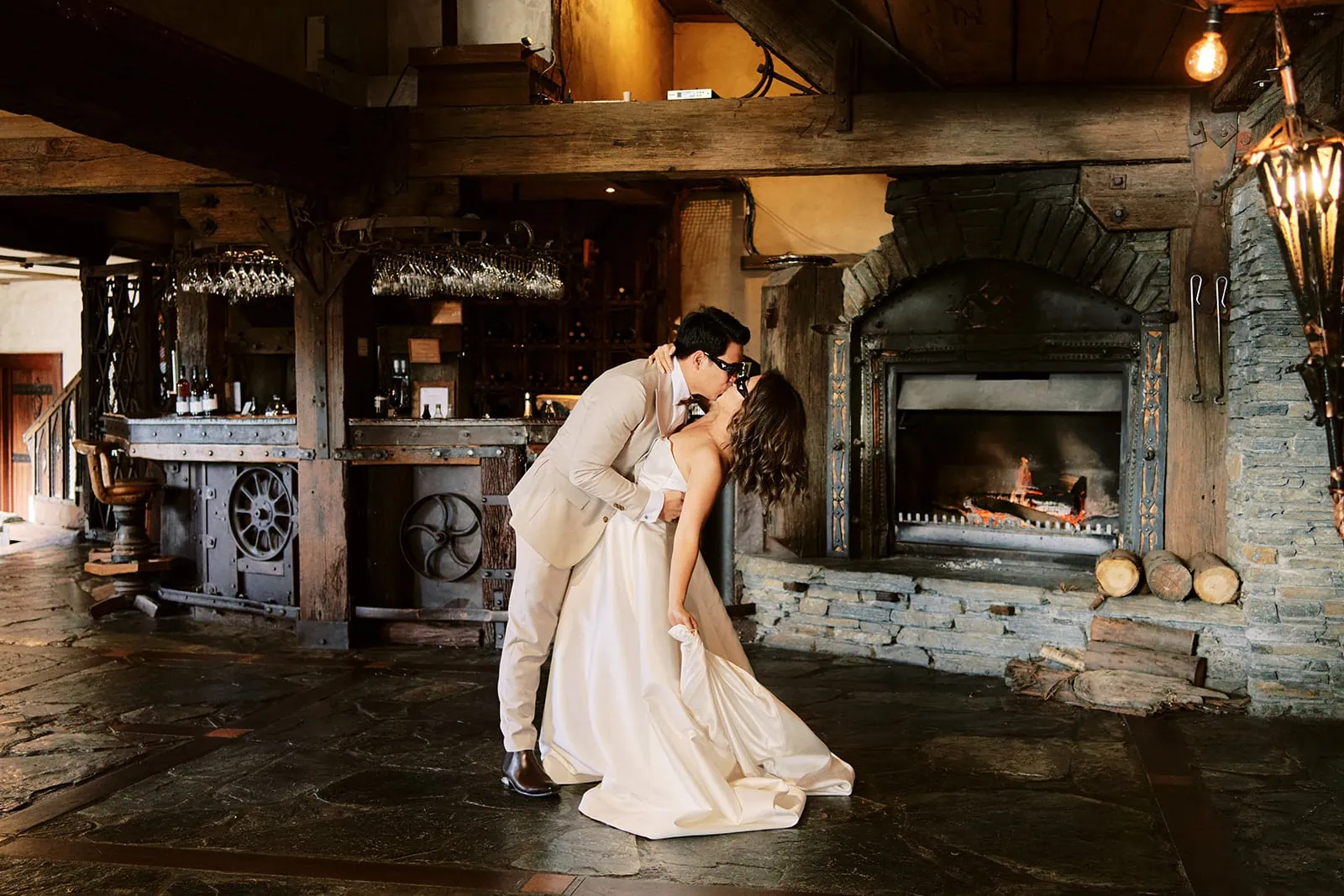 Queenstown Elopement Heli Wedding Photographer クイーンズタウン結婚式 | A Queenstown bride and groom sharing a romantic kiss in front of a fireplace at StoneRidge on their wedding day.