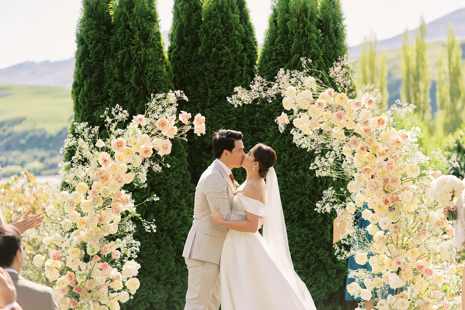 Queenstown Elopement Heli Wedding Photographer クイーンズタウン結婚式 | Ceidi and Tobi, the bride and groom, kiss under a flower arch at their Queenstown wedding.