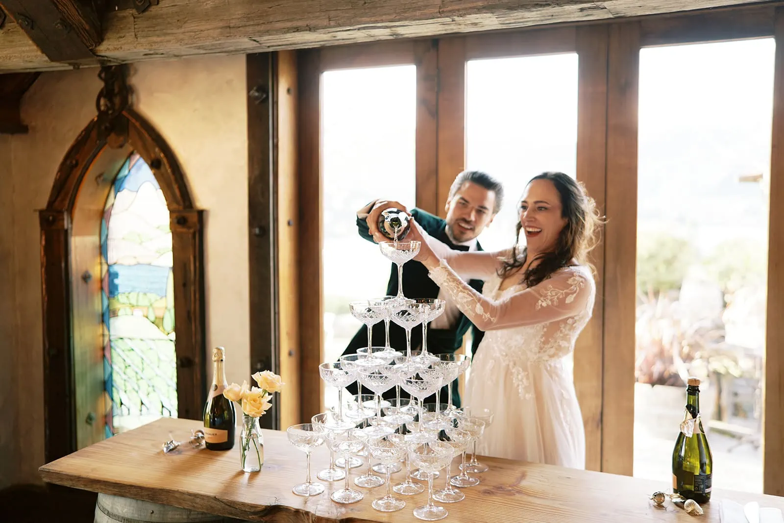 Queenstown Wedding Photographer Nat & Tim, a bride and groom, enjoying their Queenstown elopement at Deer Park Heights by pouring wine glasses at a table.
