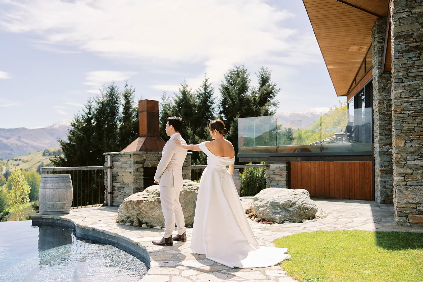 Queenstown Elopement Heli Wedding Photographer クイーンズタウン結婚式 | Queenstown Wedding - A bride and groom standing next to a pool.