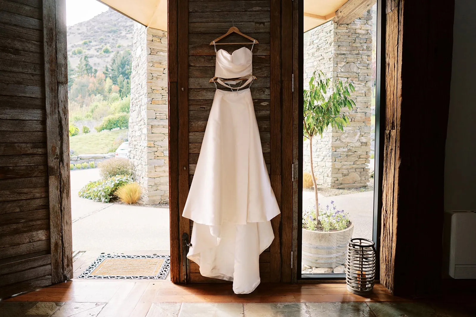 Queenstown Elopement Heli Wedding Photographer クイーンズタウン結婚式 | A Queenstown wedding dress hanging on a wooden door.