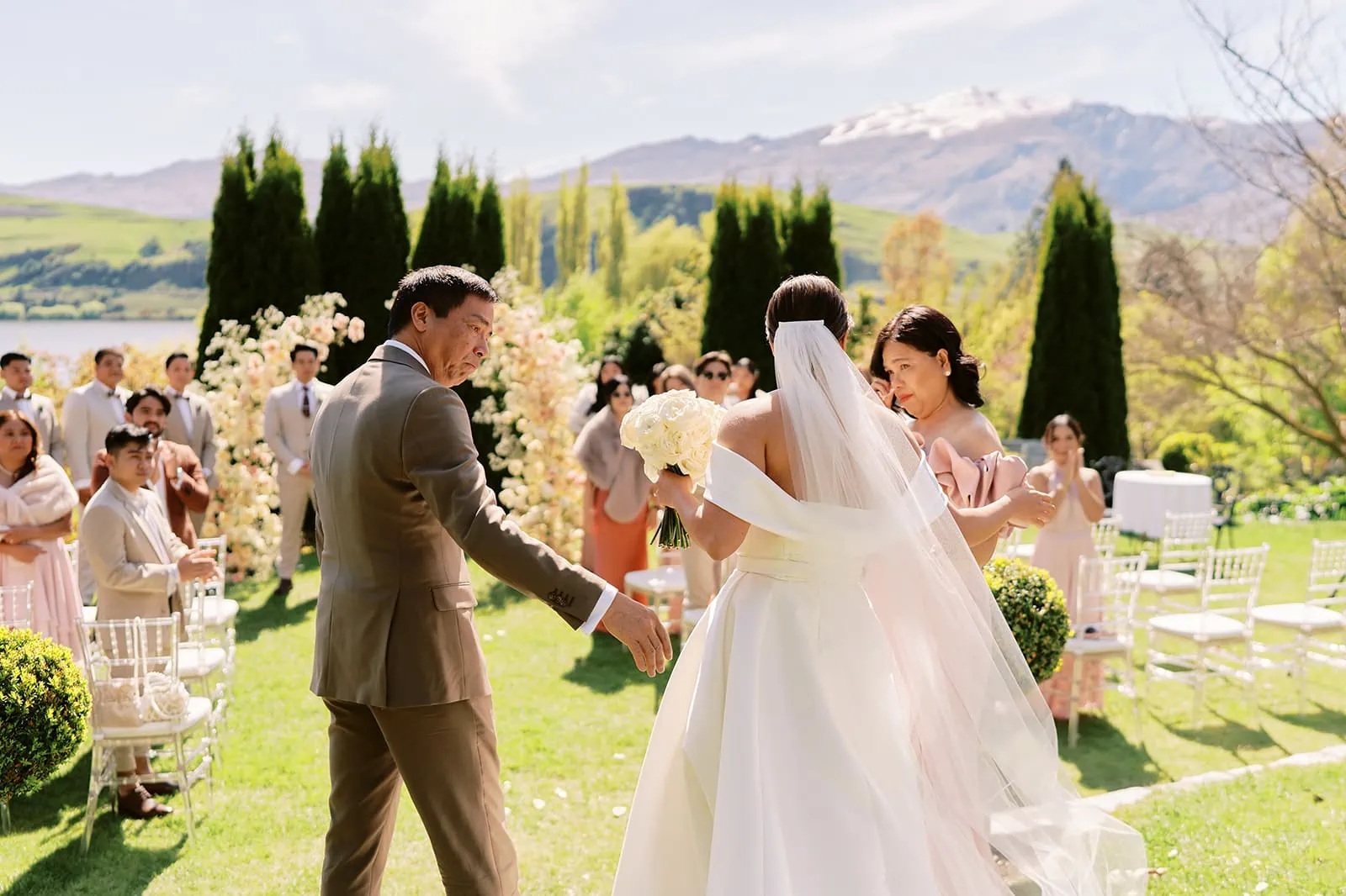 Queenstown Elopement Heli Wedding Photographer クイーンズタウン結婚式 | A wedding ceremony in a garden in Queenstown with mountains in the background.