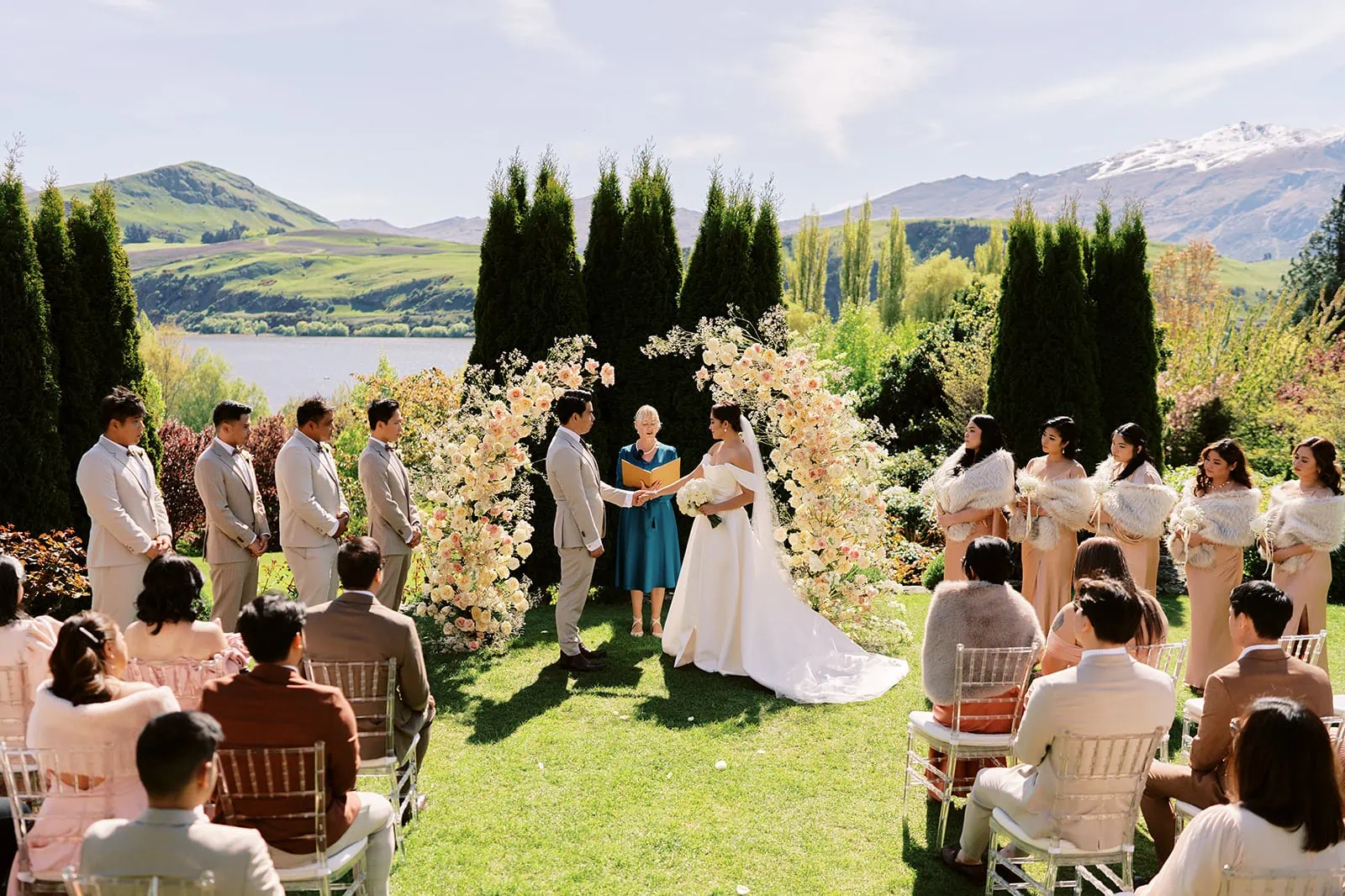 Queenstown Elopement Heli Wedding Photographer クイーンズタウン結婚式 | A wedding ceremony in a garden with mountains in the background, taking place in Queenstown.