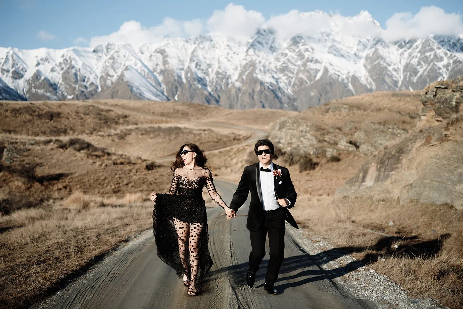Queenstown Wedding Photographer A couple enjoying a scenic stroll on a picturesque road with majestic mountains in the background, envisioning their dream Queenstown heli-wedding package.