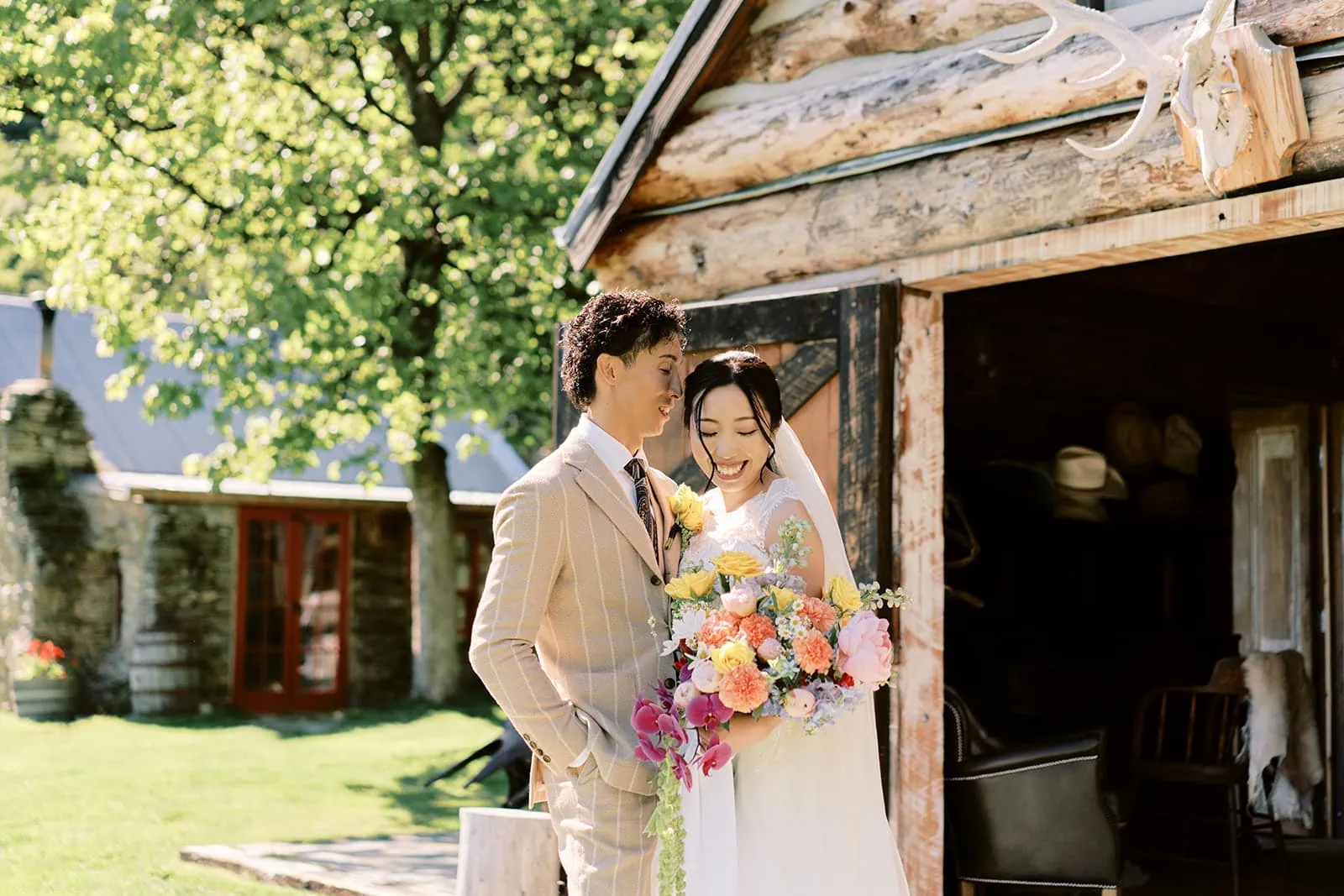 Queenstown Elopement Heli Wedding Photographer クイーンズタウン結婚式 | A bride and groom standing in front of a log cabin in Queenstown.