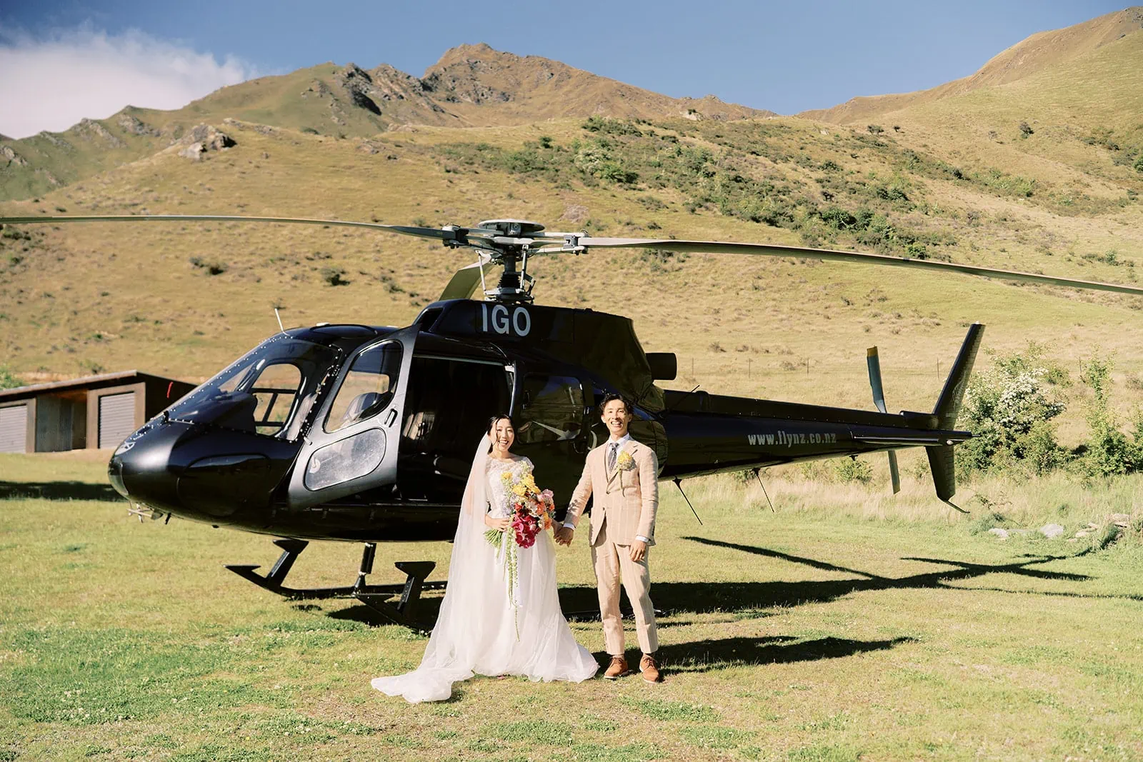 Queenstown Elopement Heli Wedding Photographer クイーンズタウン結婚式 | Queenstown newlyweds posing in front of a helicopter.
