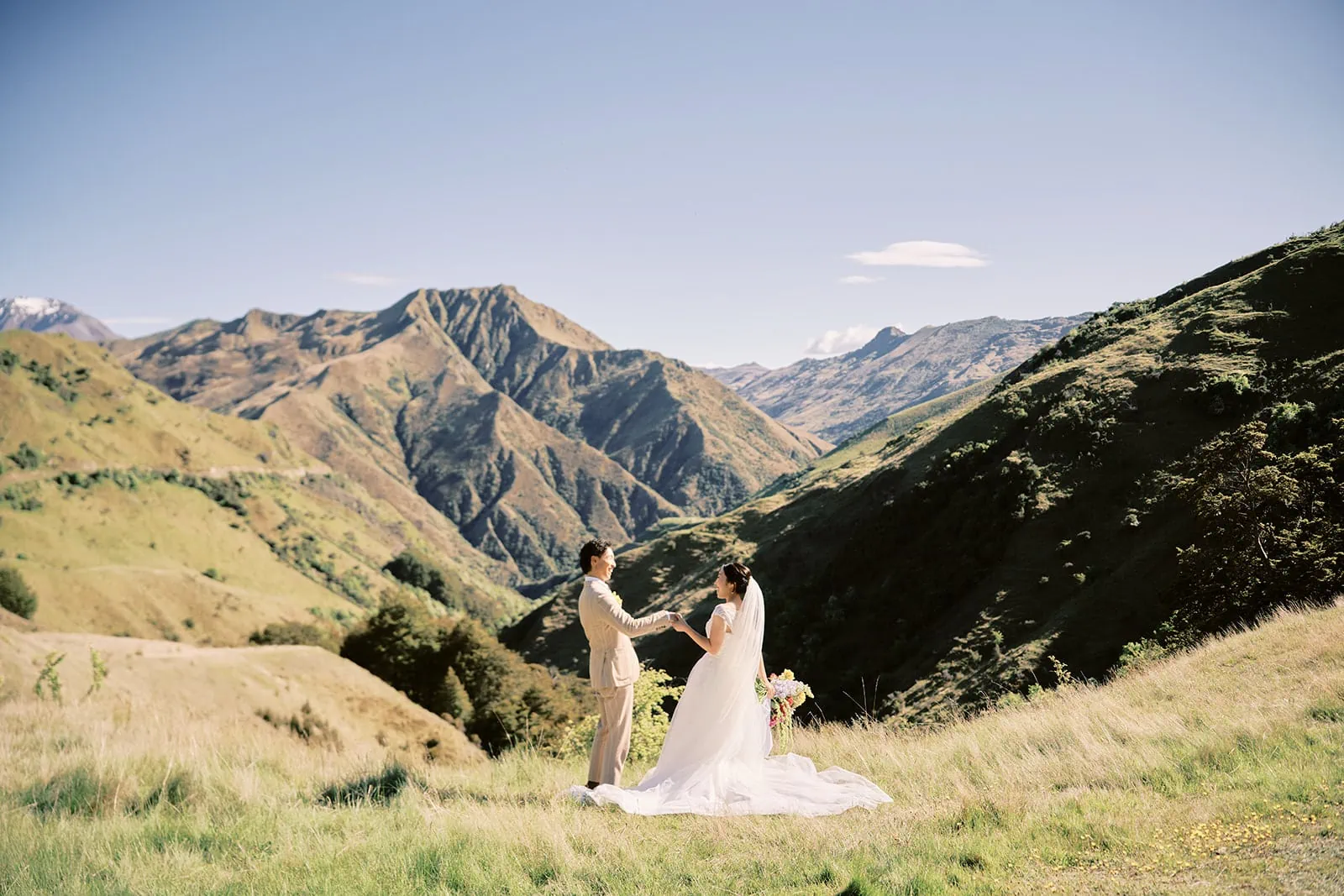 Queenstown Elopement Heli Wedding Photographer クイーンズタウン結婚式 | Taisei and Saki, a bride and groom, standing on a grassy hill in Queenstown.