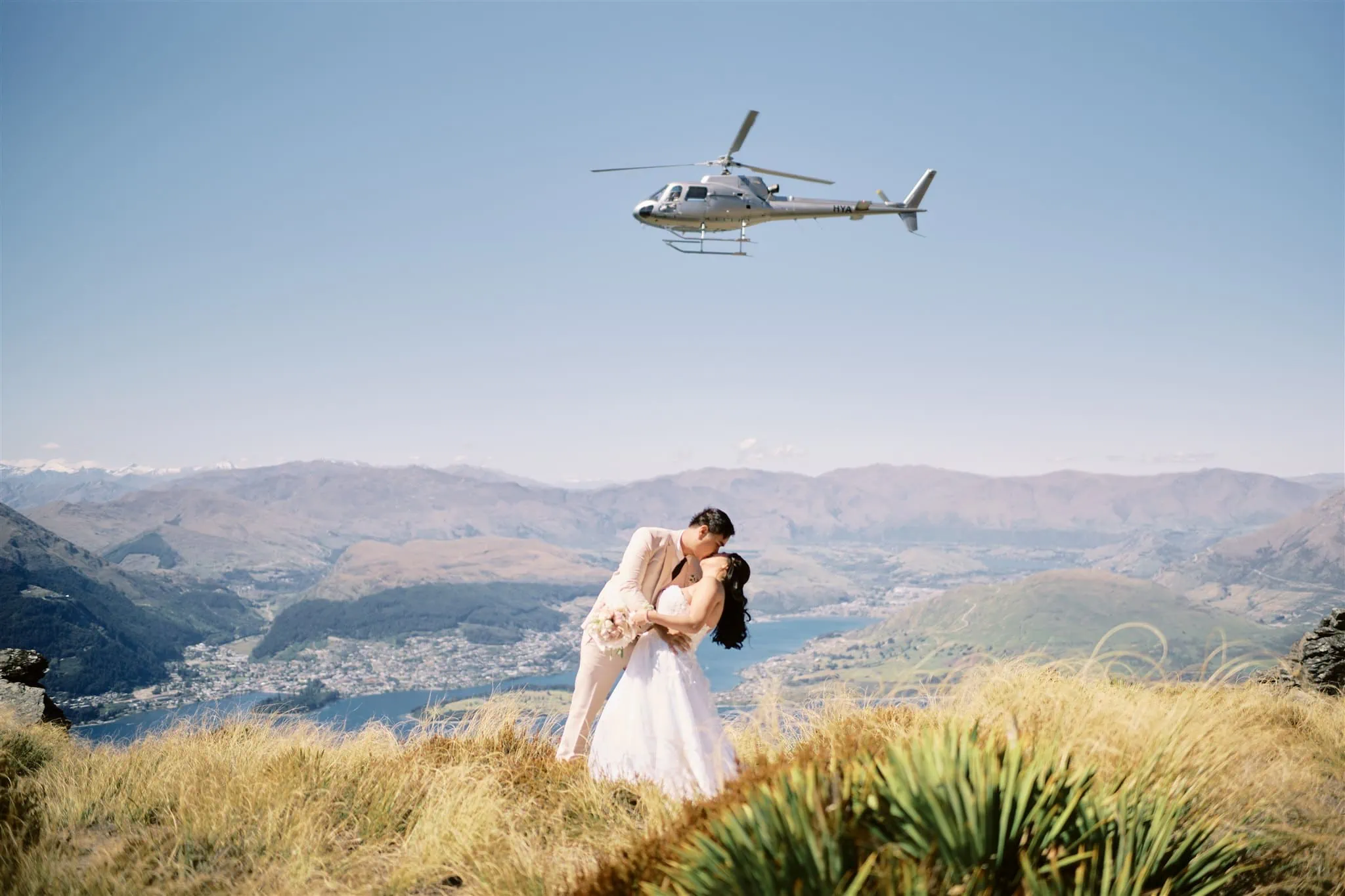 Queenstown Elopement Heli Wedding Photographer クイーンズタウン結婚式 | A couple sharing a passionate kiss during their Queenstown elopement, with a helicopter in the background.