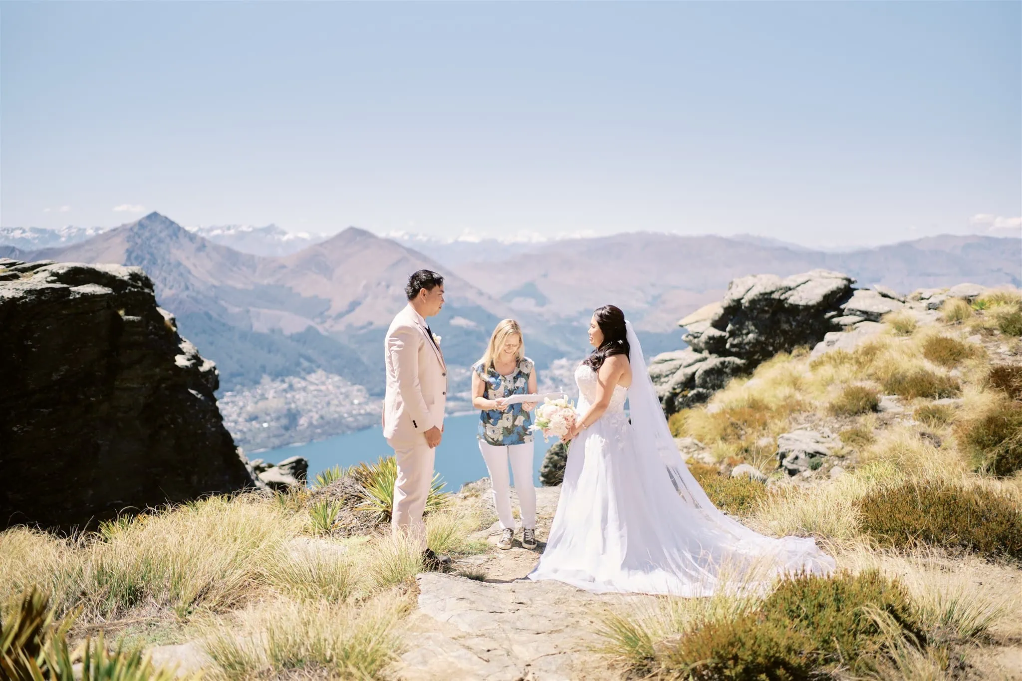 Queenstown Elopement Heli Wedding Photographer クイーンズタウン結婚式 | A group of people standing on a rock with mountains in the background during their Queenstown elopement.