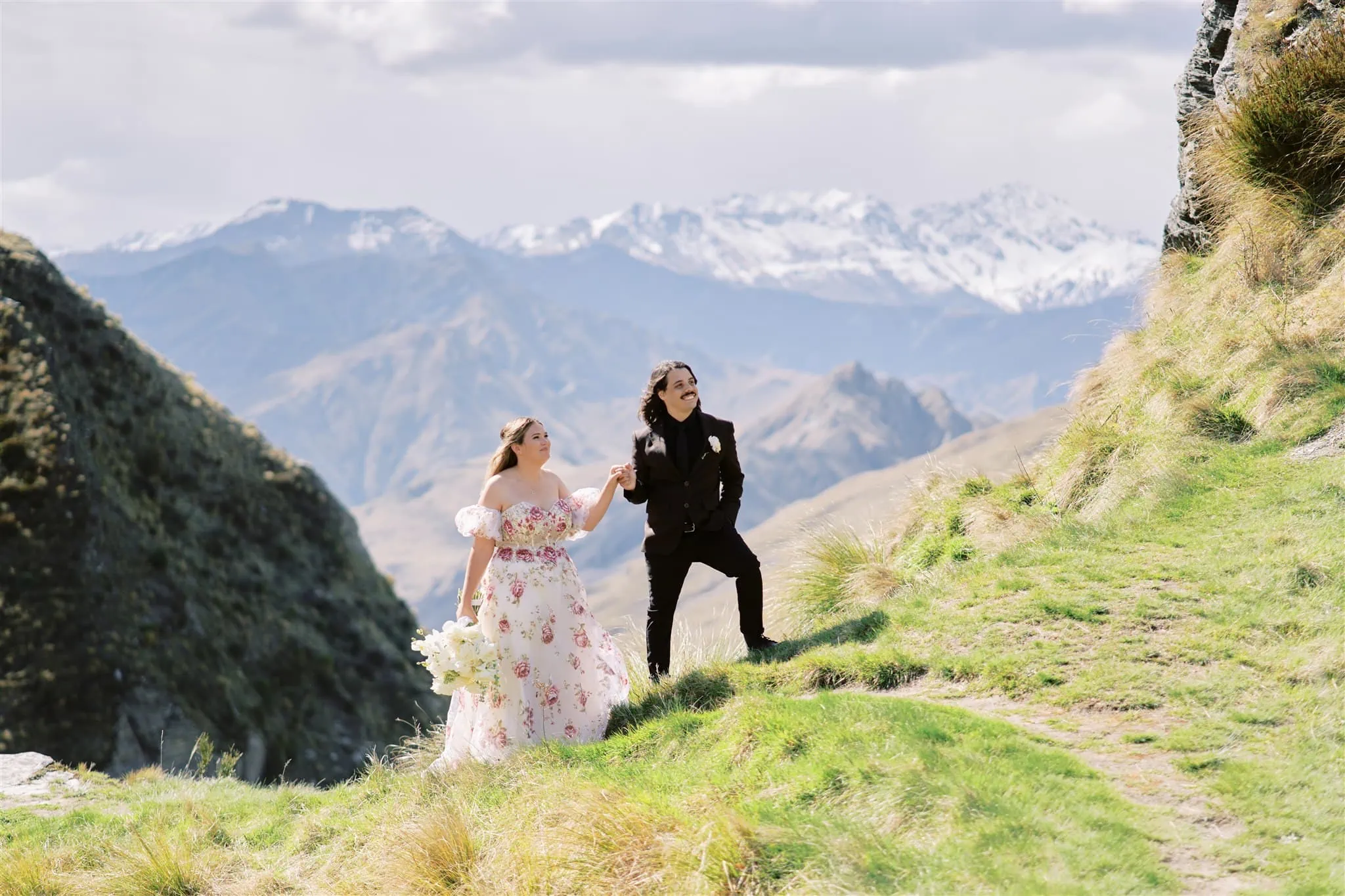 Queenstown Elopement Heli Wedding Photographer クイーンズタウン結婚式 | Two brides standing on a grassy hill with Coronet Peak in the background.