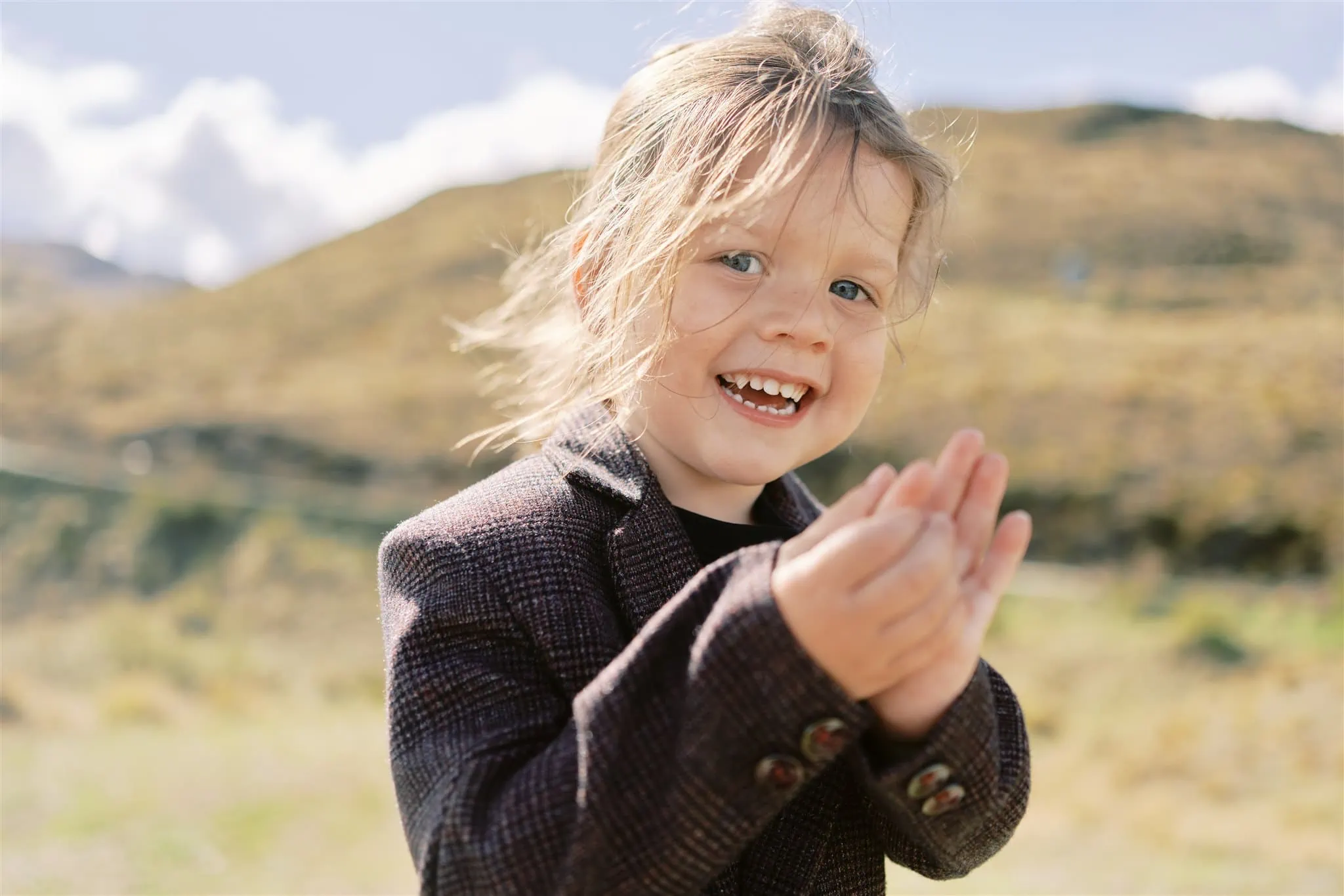 Queenstown Elopement Heli Wedding Photographer クイーンズタウン結婚式 | A little girl clapping in a field during a Coronet Peak Elopement.