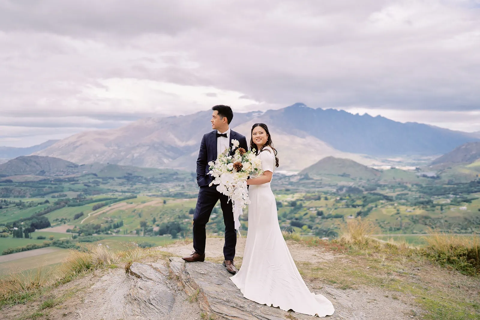 Queenstown Elopement Heli Wedding Photographer クイーンズタウン結婚式 | A bride and groom enjoying a pre-wedding photoshoot on top of a picturesque mountain in New Zealand.