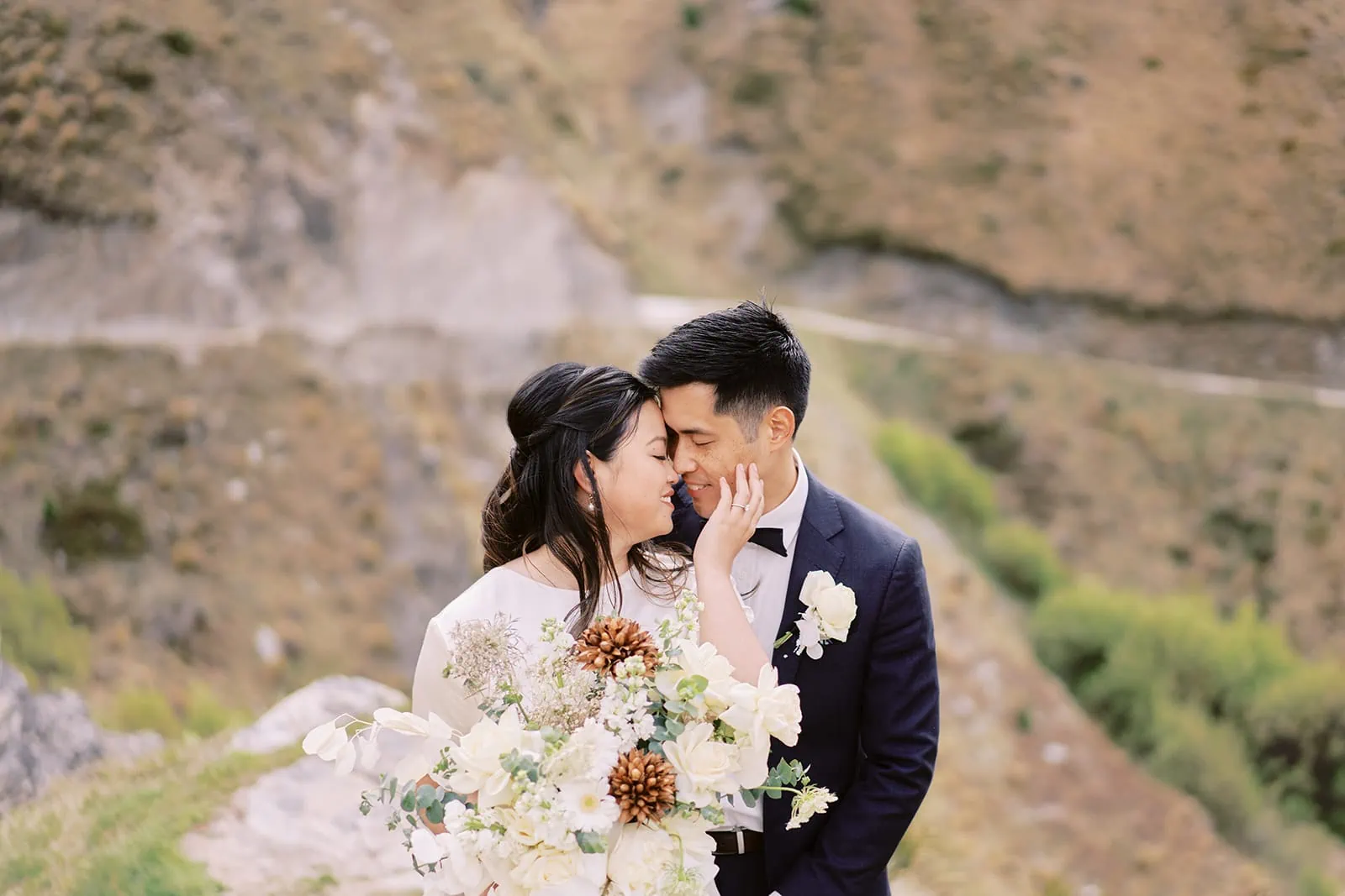 Queenstown Elopement Heli Wedding Photographer クイーンズタウン結婚式 | A couple engaging in a pre-wedding photoshoot, sharing an intimate kiss against the backdrop of a majestic mountain.