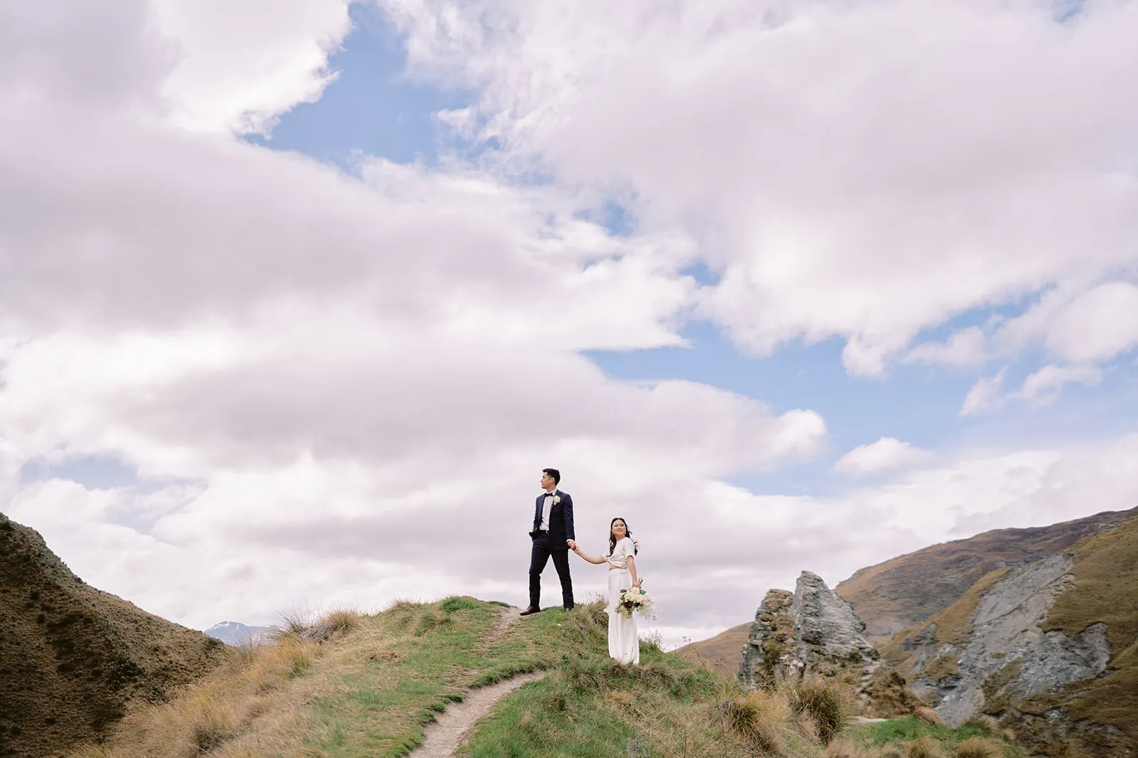 Queenstown Elopement Heli Wedding Photographer クイーンズタウン結婚式 | A man and woman posing for their pre-wedding photoshoot on a hill.
