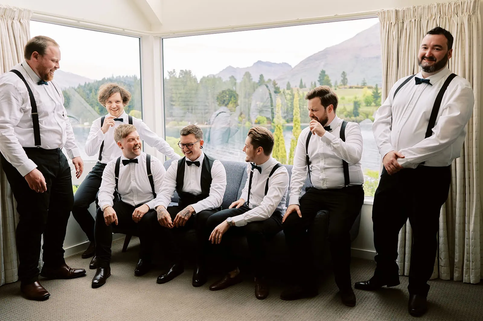 Queenstown Tekapo New Zealand Heli Wedding Elopement Pre-Wedding Shoot Photographer クイーンズタウン　テカポ　ニュージーランド　エロープメント 前撮り　フォトウェディング　結婚式 | A group of well-dressed individuals with bow ties sharing a light-hearted moment indoors during their Queenstown elopement.