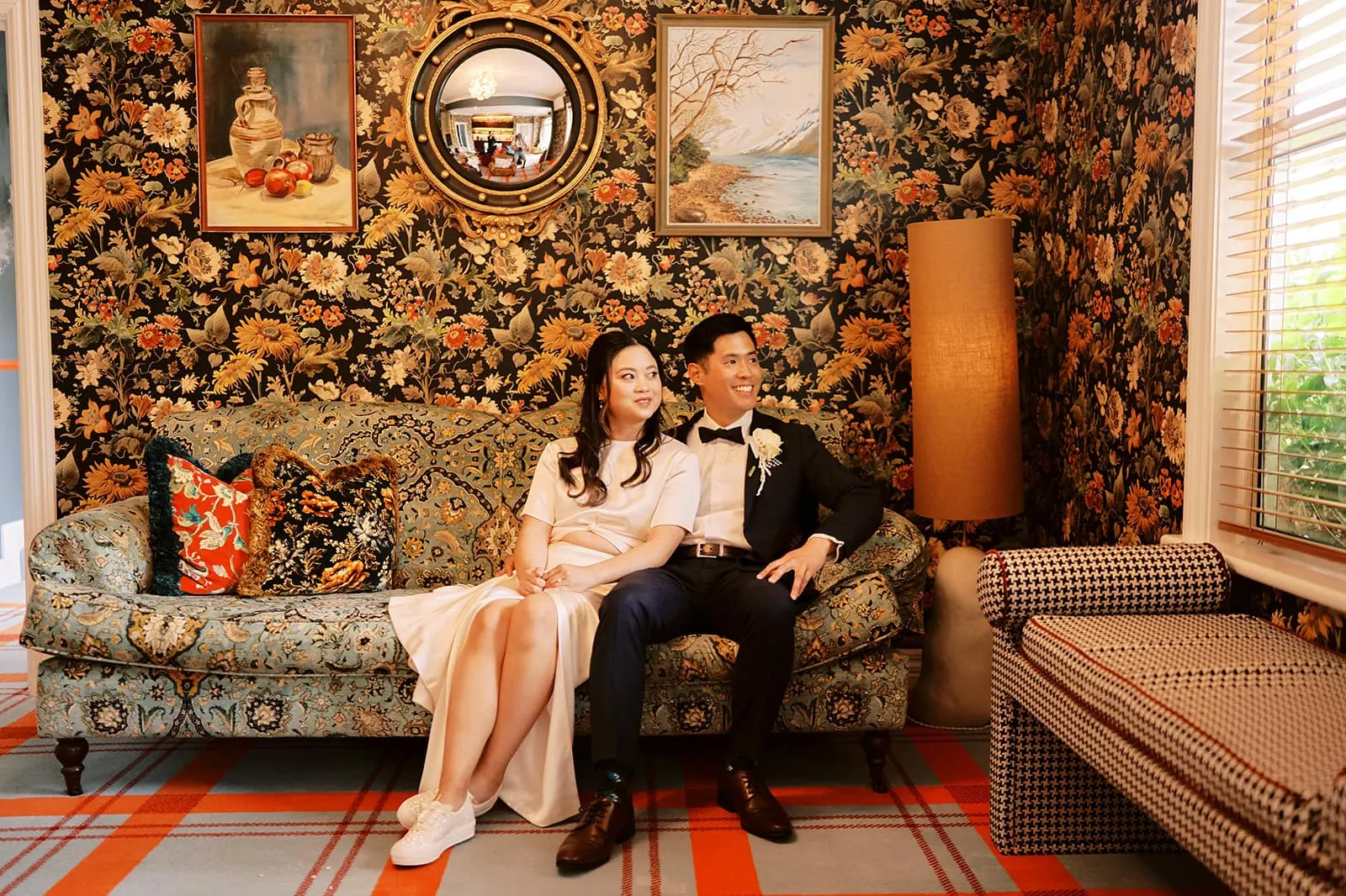 Queenstown Elopement Heli Wedding Photographer クイーンズタウン結婚式 | A couple's pre-wedding photoshoot captures the bride and groom sitting on a couch in a room adorned with elegant floral wallpaper.