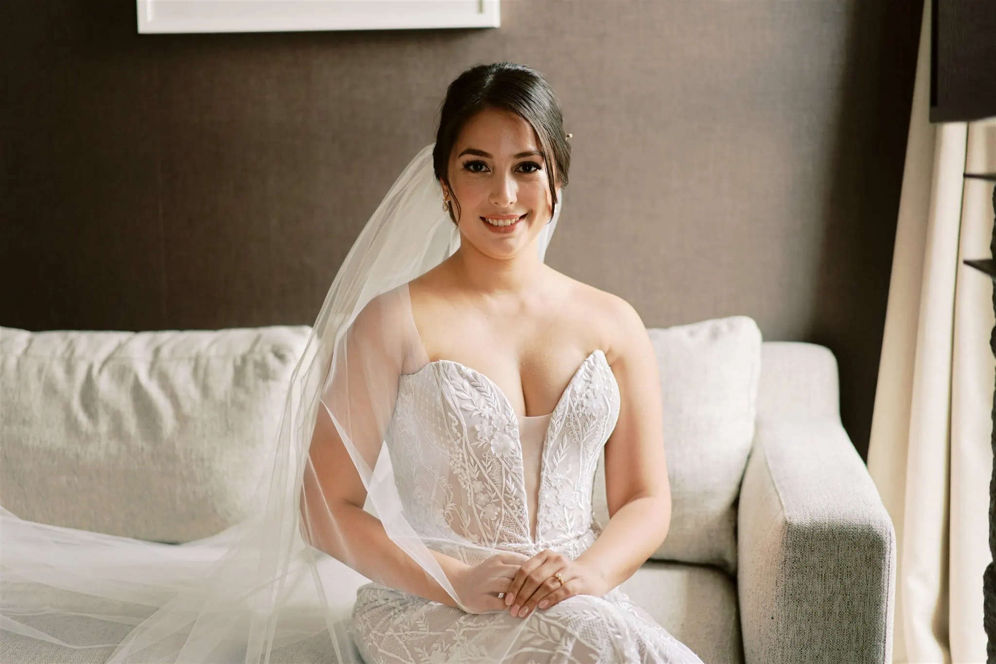 Queenstown Elopement Heli Wedding Photographer クイーンズタウン結婚式 | Mariah, a bride in a white wedding gown, elegantly sitting on a couch.